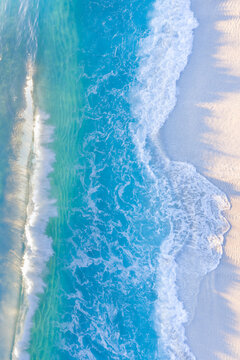 Sunlit waves rolling onto beach