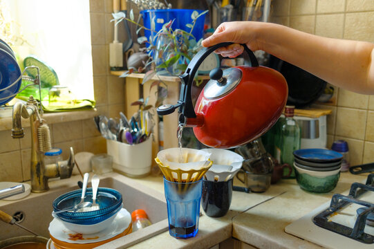 Female hand pouring water into coffee filters in glasses