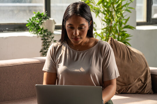 Focused Woman Working On Laptop While Sitting on the Couch
