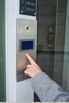 Person pressing intercom at an entrance of a building