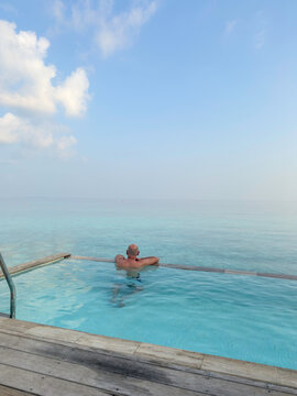 Man in a pool villa looking over the Indian Ocean in the Maldives