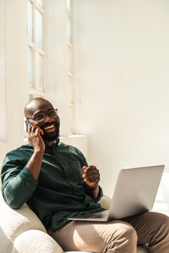 Smiling Professional Man Working on Laptop While Talking on the Phone