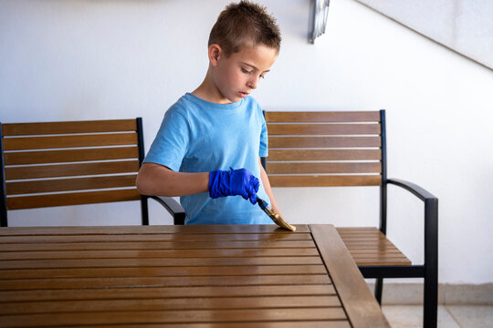Focused Child Applying Wood Stain
