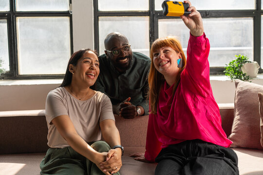 Three Friends Taking a Happy Selfie Together on a Couch in the Office