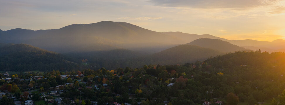 Golden morning light streaming through mountain peaks above a town