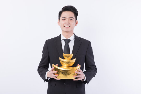 Young businessman holding stacked gold sycee ingots symbolizing wealth and prosperity