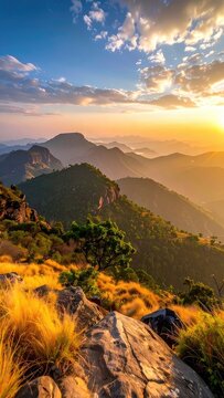 Golden hour illuminates a vast mountain range with rolling hills and lush vegetation.