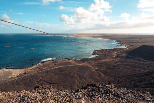 Dramatic hillside view of coastline and zipline over bay at sunset on Sal Island