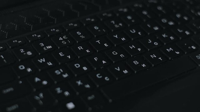 Macro view of a hand wiping wet black keyboard keys with a cotton pad. The detailed cleaning action demonstrates the removal of germs and moisture for device sanitation.
