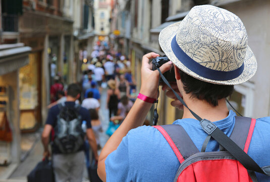 Back view of a young tourist taking photos of a crowded street in Venice Italy