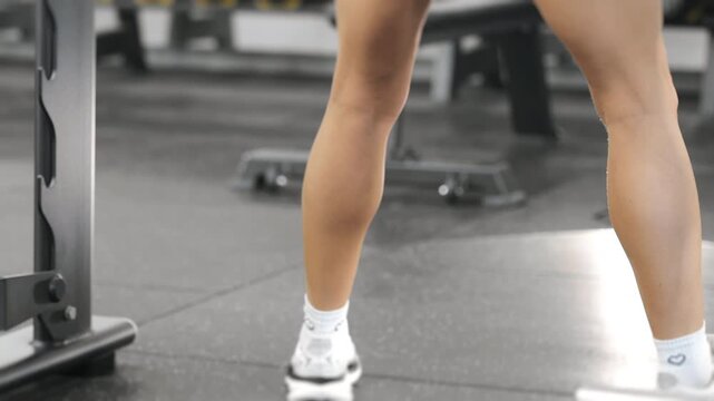 Close up of athletic woman performing squat exercise during strength training workout in fitness center. Focus on lower body development, endurance and healthy lifestyle.