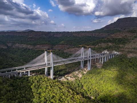 Aerial view of the Mumbai-Pune Expressway Missing Link Project featuring cable-stayed bridges under construction amidst lush green hills and tunnels in Khopoli, Maharashtra, India.