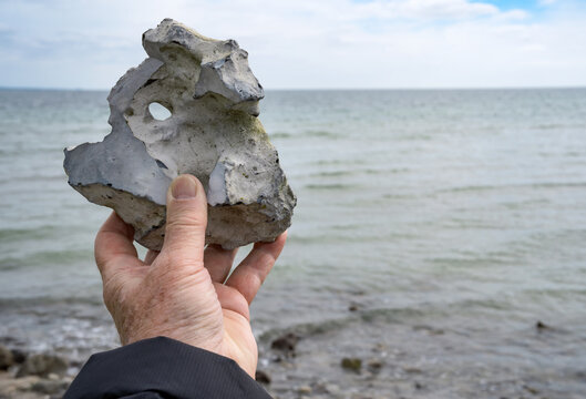 Detail of a hole stone with view through and a hand. Erosion pattern with natural beauty on danish baltic coast.