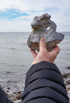 Detail of a hole stone with view through and a hand. Erosion pattern with natural beauty on danish baltic coast. Vertical background. 
