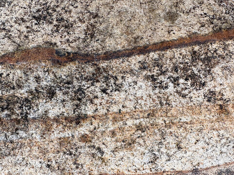 Wide landscape view of clean natural stone texture background. Rough weathered rock surface with linear brown iron oxide patterns. Perfect backdrop space for product overlay.