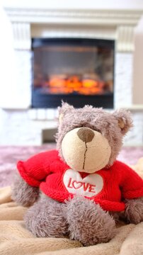 Plush teddy bear  by the fireplace, cozy living room, soft blanket is draped over the armchair, quietly enjoying the serene atmosphere. Happy time at the home.