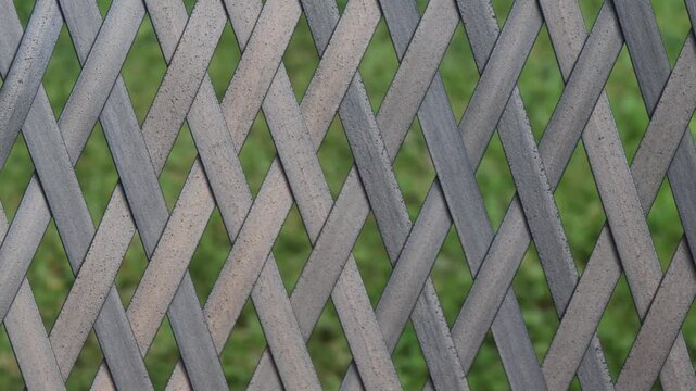 Vertical Pan Across Grey Garden Lattice Fence Pattern with Green Background