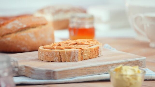 Peanut butter spread on fresh bread slice, homemade breakfast preparation, copy space