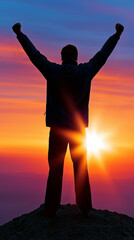 Fototapeta premium Silhouette of a successful person raising arms in triumph on a mountain peak at sunrise symbolizing achievement and motivation.