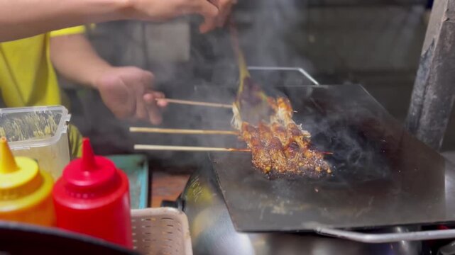 Person grilling meat on a metal skewer in a kitchen