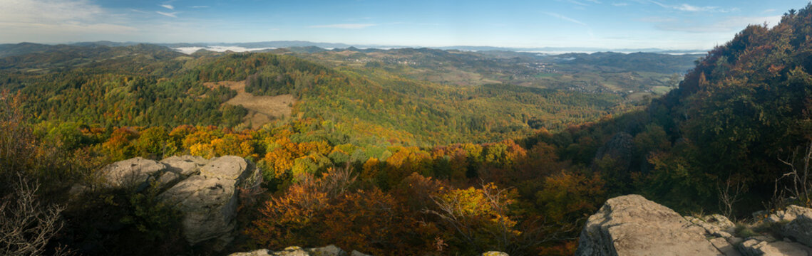 Aerial view of the autumn landscape of Tatarska luka with vibrant colorful forest canopy, rocky outcrops in the foreground, and rolling hills in Ilija, Banska Bystrica Regio, Slovakia.