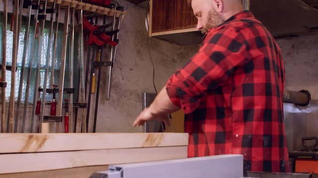 Lumber workshop. Furniture making. Male joiner preparing smoothed plank for diy project in carpentry equipped with professional tools.