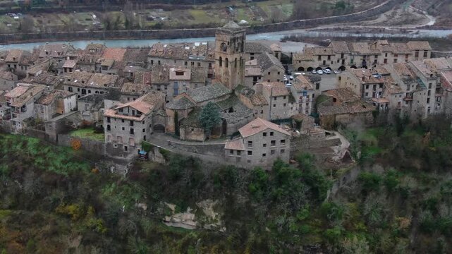 Aerial view showcasing the beautiful medieval town of Ainsa. Historic stone houses and a church sit on a hill above a river in Aragon, Spain