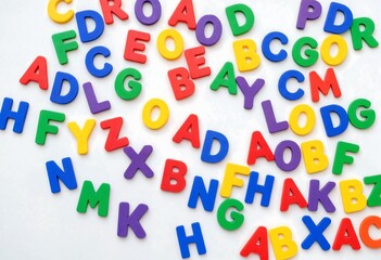 Fototapeta premium Colorful alphabet letters scattered across a clean white background with selective focus