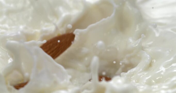 Almonds falling into milk with splash in super slow motion