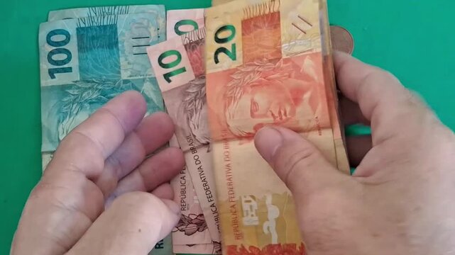 Hands counting Brazilian real banknotes and coins in motion video