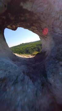 Cinematic FPV drone flight through a natural rock arch at Maczuga Herkulesa in southern Poland. Unique limestone formation surrounded by forest in the Jura region.