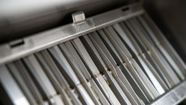 Kitchen hood filter sits removed for maintenance to ensure proper grease extraction and safety in the cooking area.