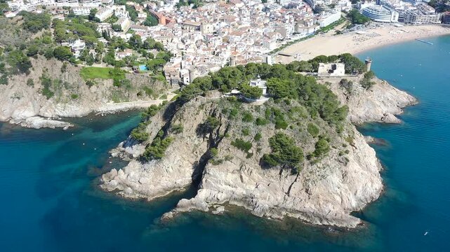 Aerial view of Tossa de Mar, his lighthouse and the beautiful Cala Es Codolar beach with turquoise Mediterranean waters. 