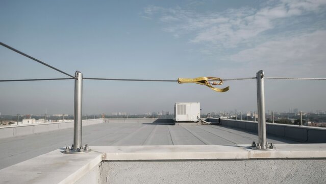Safety railing with a tensioner installed on a building rooftop provides fall protection for maintenance workers.