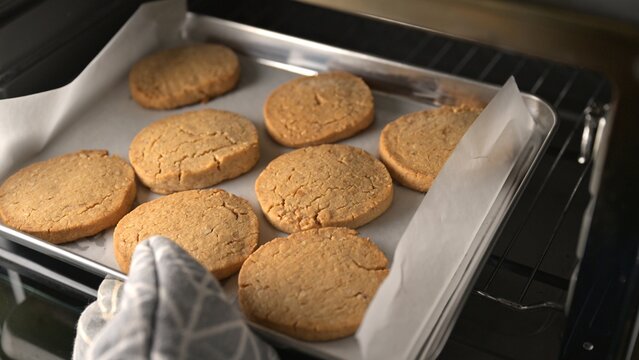 Nut and peanut butter shortbread cookies on baking tray with parchment paper inside oven. Food photography. Homemade bakery and cookie baking concept. Close-up shot.