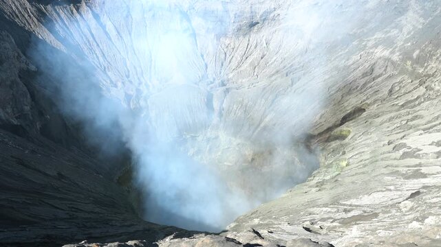 Smoking volcanic crater with sulfur fumes and steep rocky walls