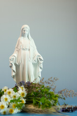Virgin Mary statue with traditional herb bouquet, Assumption Day  celebration concept with natural floral foreground