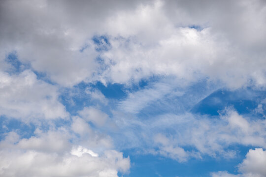 Beautiful blue sky background with fluffy white and grey cumulus clouds.