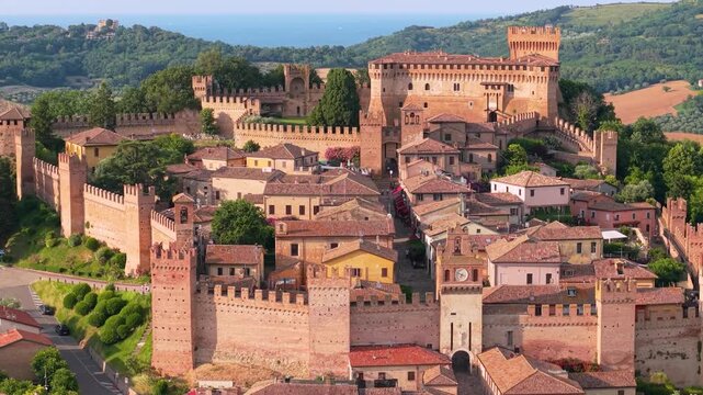Gradara Castle Marche Italy 4K Drone. Camera tilt up on 70mm lens revealing fortified medieval borgo town walls. Borghi piu belli d Italia most beautiful villageыб side flight footage