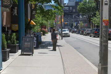Naklejka premium looking south on McCaul St with sidewalk a-frame sign and signage outside Tuck Shop Provisions, a coffee shop, located at 29 McCaul, Toronto