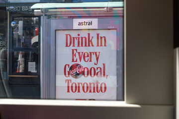 Obraz premium OOH bus shelter advertising poster for Coca-Cola seen from inside a trolley heading eastbound on Dundas St W, Toronto