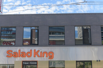 Naklejka premium exterior building facade and neon sign of Salad King, a Thai restaurant, located at 224 Queen St W, Toronto (McCaul St entrance)