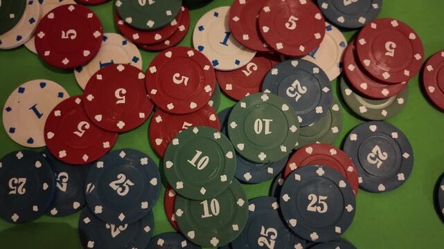 A close-up top-down view of poker chips scattered across a classic green felt table. The chips are in various denominations and colors, including red, blue, green, and white. The mood is one of
