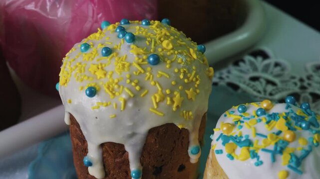 Traditional Easter cakes stand decorated with white icing and bright blue and yellow sprinkles. Concept of religious traditions, spring holiday preparation, and patriotic colors.