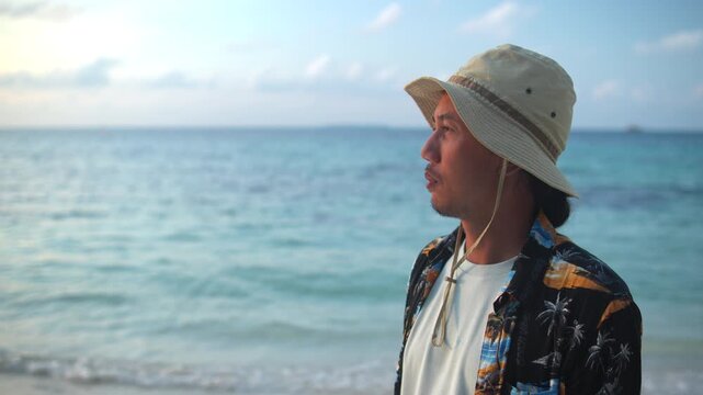 Contemplative Man Wearing a Sun Hat on a Tropical Beach at Sunset, Gazing Over the Calm Ocean, Symbolizing Peace, Reflection, Mindfulness, Freedom, and a Relaxed Coastal Lifestyle
