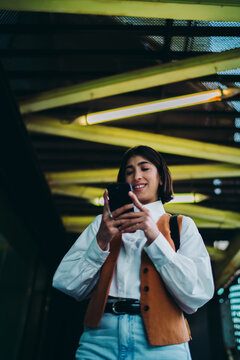 Happy latin female remote worker browsing web page news feed smartphone application software. Smiling mixed race student typing chat text messages over 5G internet wireless data network connection.