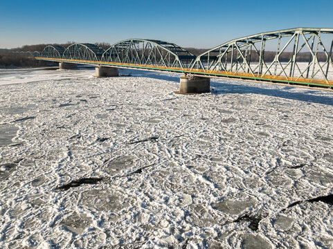 Metal bridge with traffic over a river with ice floes.