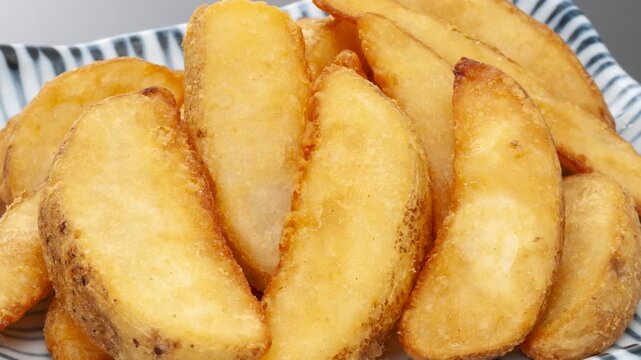 Golden crispy wedge cut french fries on Japanese pattern plate with pan and zoom camera movement