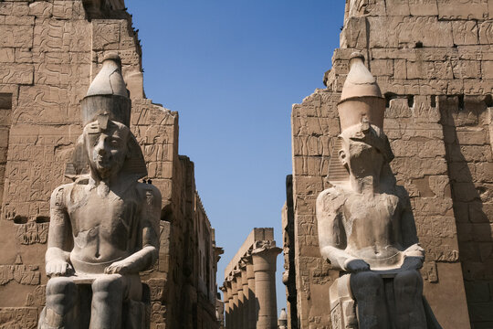 Majestic ancient stone statues of Ramesses II guarding the entrance avenue inside Luxor Temple Egypt
