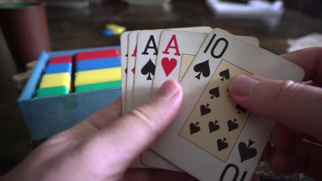Hands holding playing cards reveal a winning poker hand of four aces and a ten
